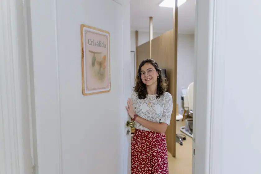 Dra. Priscila Lugarinho recebendo a paciente à porta da sala de consulta, com um sorriso acolhedor
