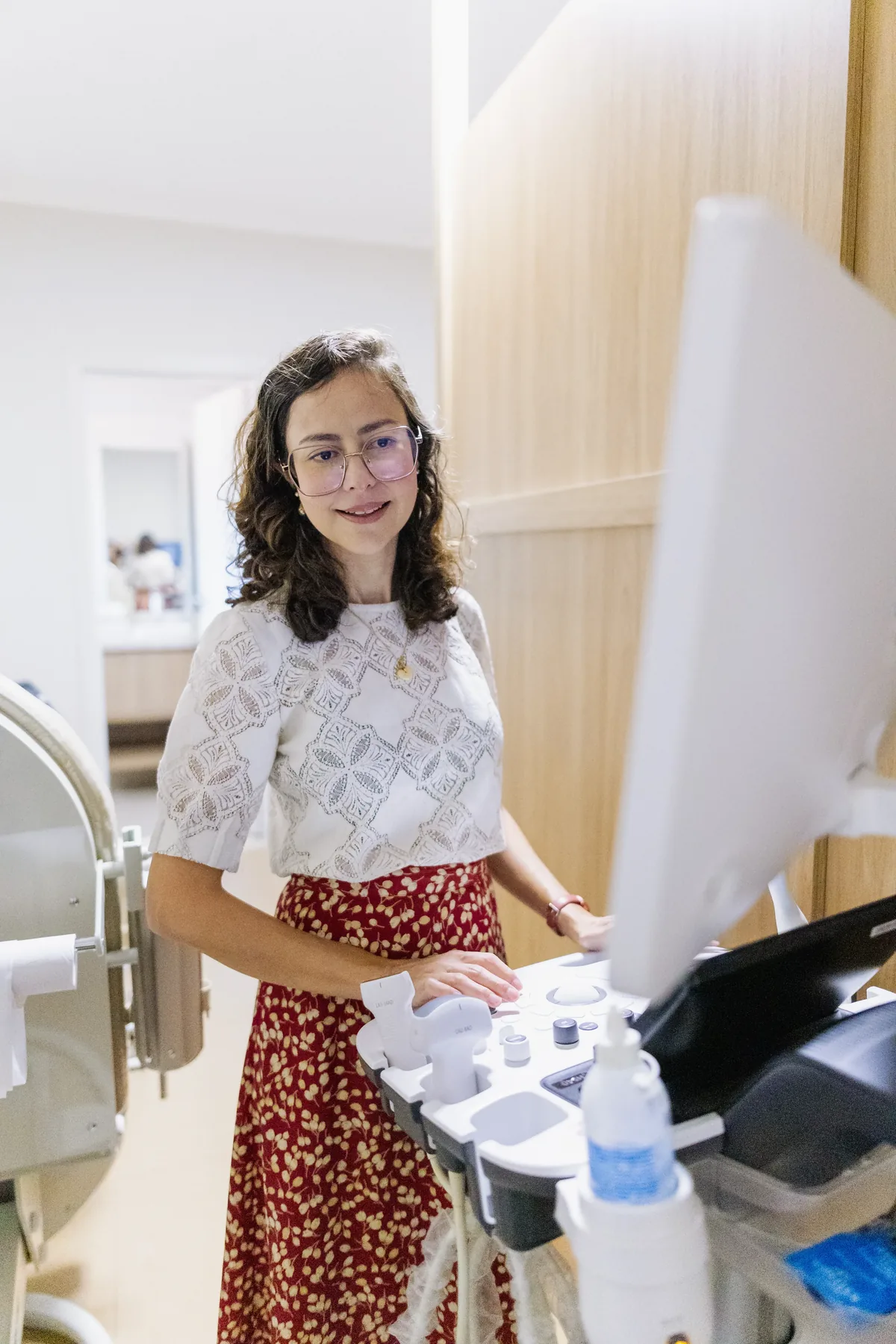 Dra. Priscila Lugarinho ao lado do aparelho de ultrassom, durante o acompanhamento obstétrico.