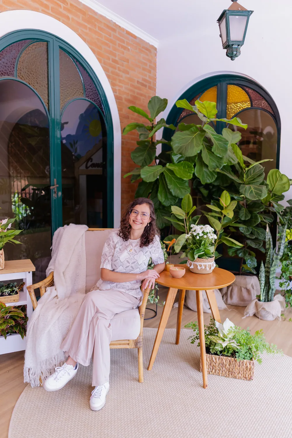 Dra. Priscila Lugarinho sentada na varanda do Espaço Casulo, cercada de plantas