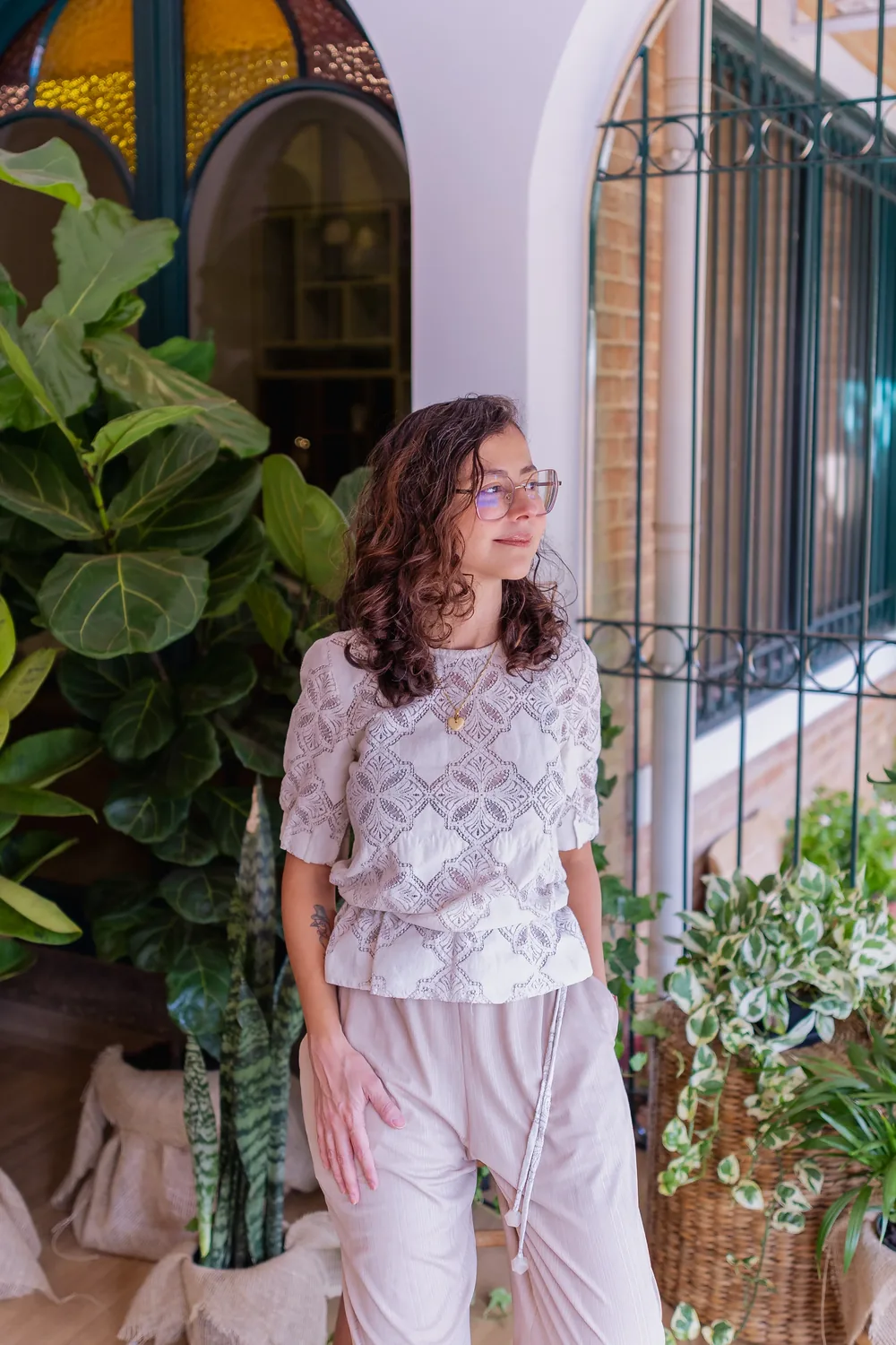 Dra. Priscila Lugarinho em pé na varanda do Espaço Casulo, entre as plantas