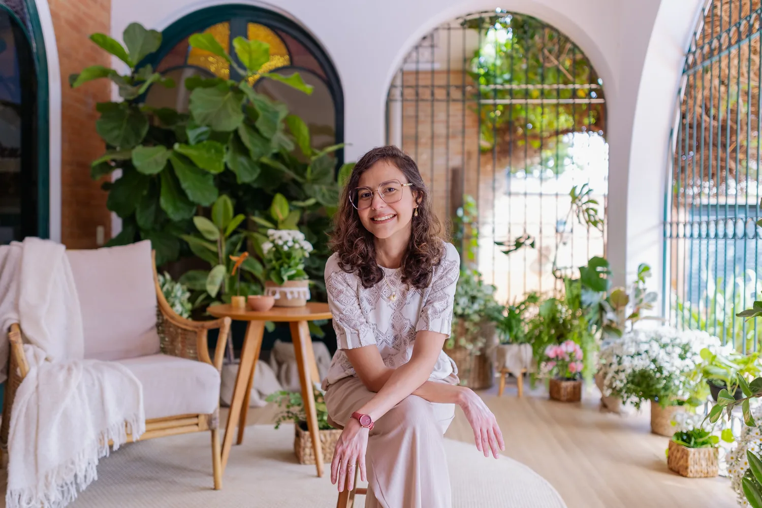 Dra. Priscila Lugarinho sorrindo, sentada na varanda do Espaço Casulo